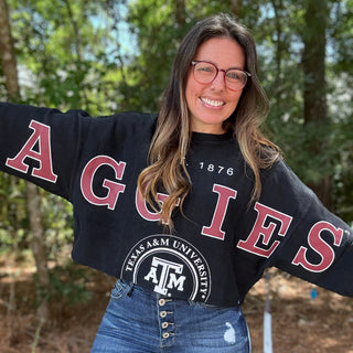 Person wearing a black 'AGGIES' sweater with Texas A&M University logo outdoors-ava wray boutique