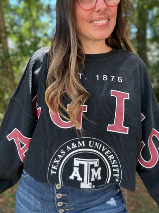 Person wearing a black Texas A&M University sweatshirt with a blurred outdoor background-ava wray boutique