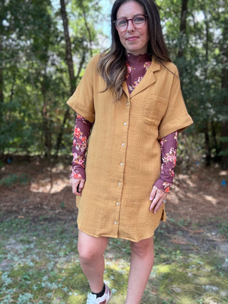 Woman wearing a mustard yellow dress with floral sleeves in a forest setting- ava wray boutique
