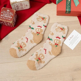 Pair of Christmas-themed socks on a wooden surface with gift boxes in the background.