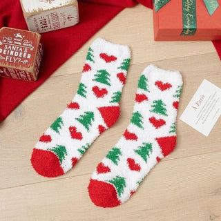 Christmas-themed socks with red and green patterns on a wooden surface with gift boxes and cards.