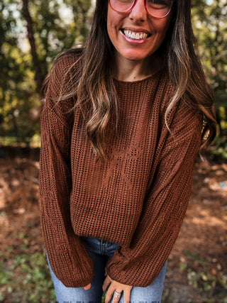 Woman wearing a brown sweater and jeans outdoors with trees in the background-ava wray boutique