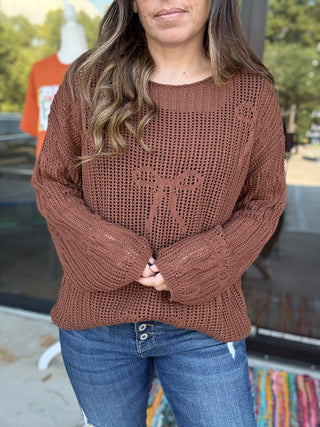 Person wearing a brown knitted sweater and blue jeans outdoors.-ava wray boutique