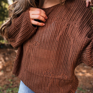 Brown knitted sweater worn by a person with a blurred natural background- Ava Wray Boutique