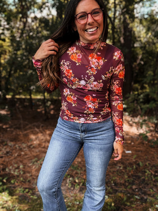 Woman wearing a floral long-sleeve top and jeans standing in a forest-ava wray boutique