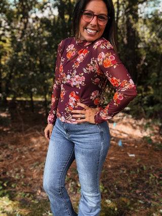 Woman wearing a floral long-sleeve top and jeans standing outdoors with trees in the background-ava wray boutique