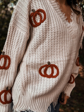 Beige sweater with brown pumpkin designs worn by a person outdoors-ava wray boutique