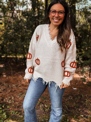 Woman wearing a white sweater with orange pumpkin patterns outdoors-ava wray boutique