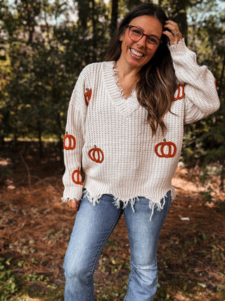 Woman wearing a white sweater with orange pumpkin patterns outdoors-ava wray boutique
