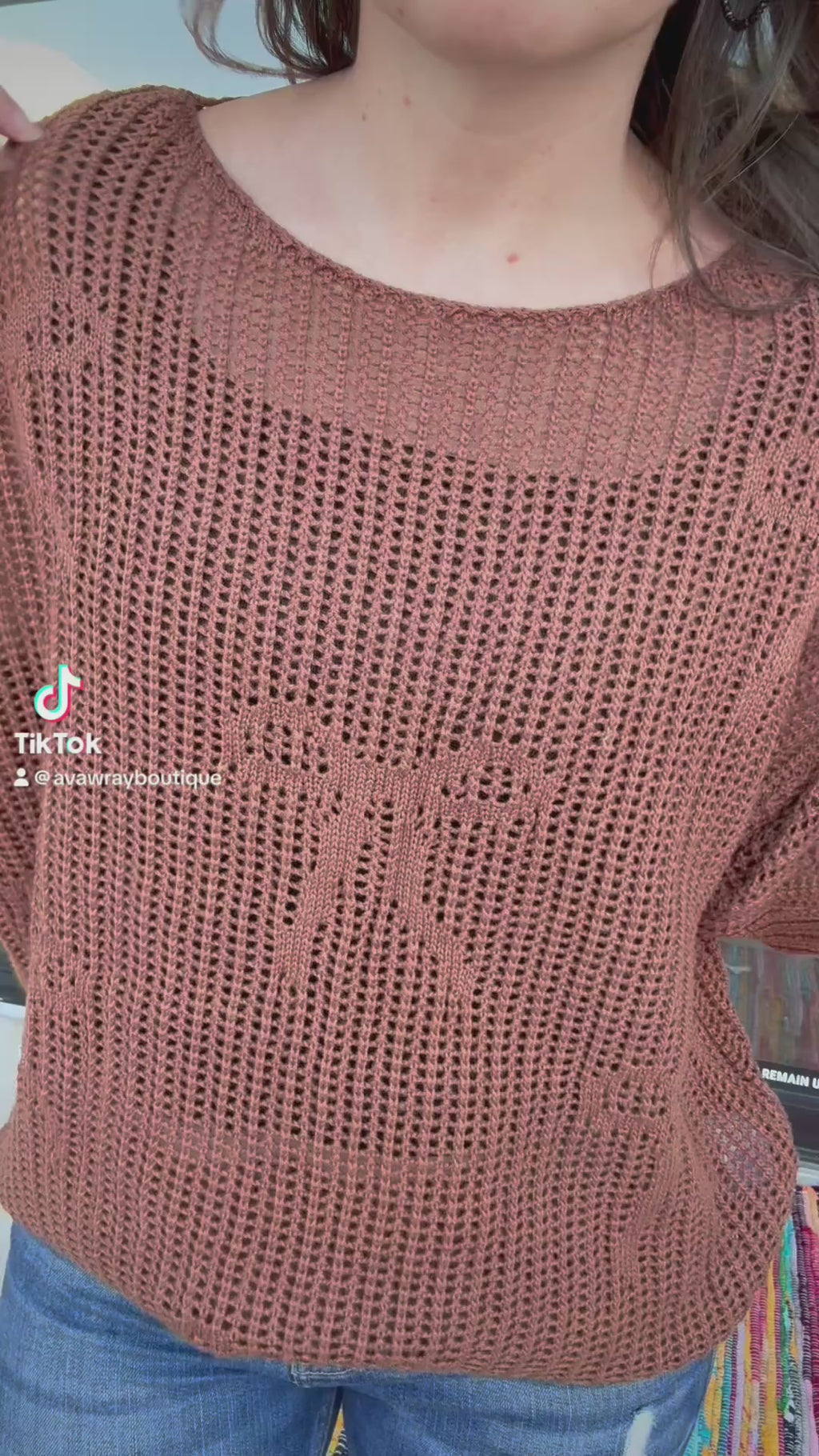 Person wearing a brown knitted sweater and blue jeans outdoors.- ava wray boutique