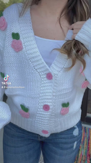 Person wearing a white knitted cardigan with pink floral patterns outdoors-ava wray boutique