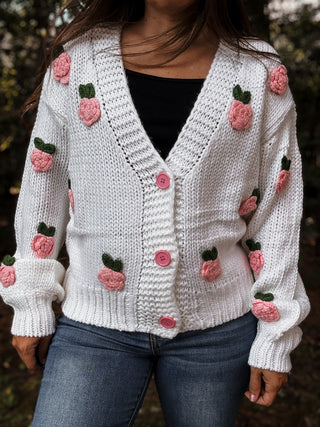 White knitted cardigan with pink floral embellishments worn by a person outdoors-ava wray boutique