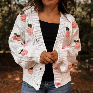 Person wearing a white knitted cardigan with pink floral embellishments outdoors-ava wray boutique